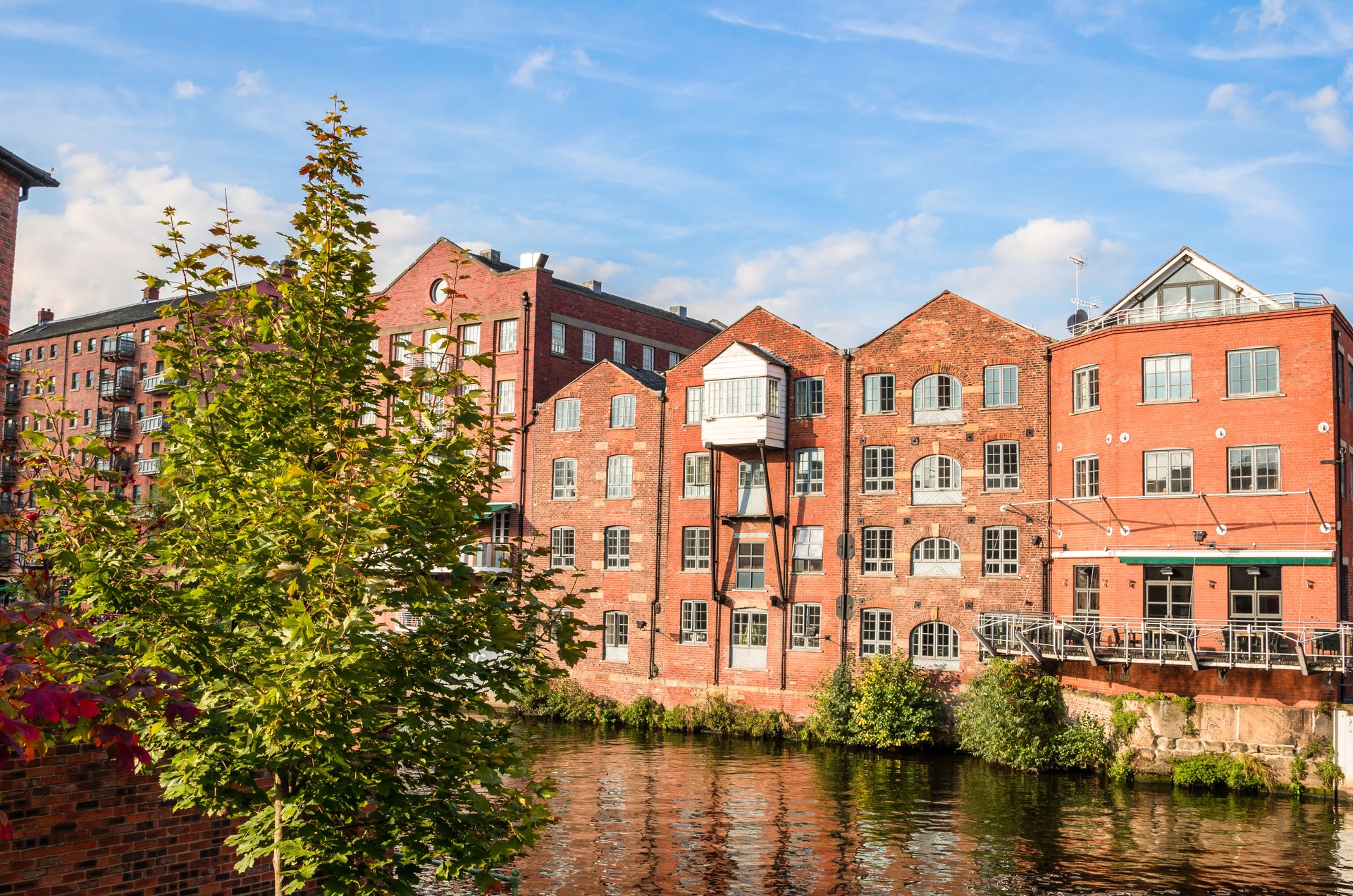 Renovated brick buildings along a river on a clear autumn day